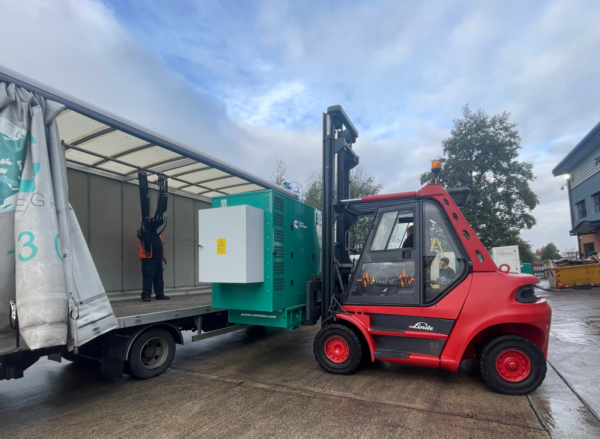 A red Linde forklift lifting a green generator onto a lorry truck ready to be transported for a generator servicing job.