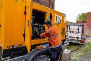 Pleavin Power team member making repairs to diesel generator